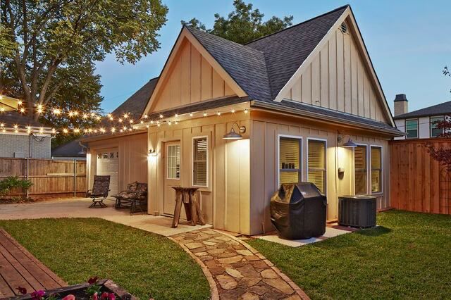 Backyard cottage with board-and-batten siding, string lights and stone path